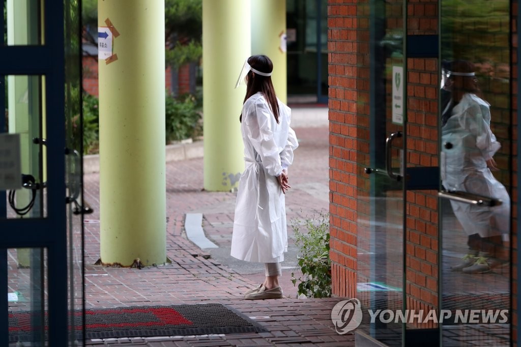 Une personne du bureau de vote installé à l'école primaire de Gyesu dans la ville de Gwangju, attend les électeurs atteints du nouveau coronavirus (Covid-19), après 18h30 le mercredi 1er juin 2022, dans le cadre des élections locales.