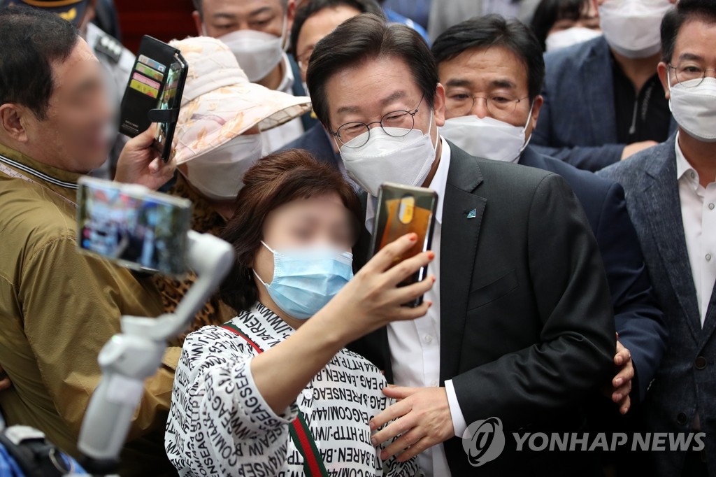 The main opposition Democratic Party Chairman Lee Jae-myung (C) takes a selfie with a citizen at a traditional market in Gwangju, about 270 kilometers south of Seoul, on Sept. 2, 2022. (Yonhap)