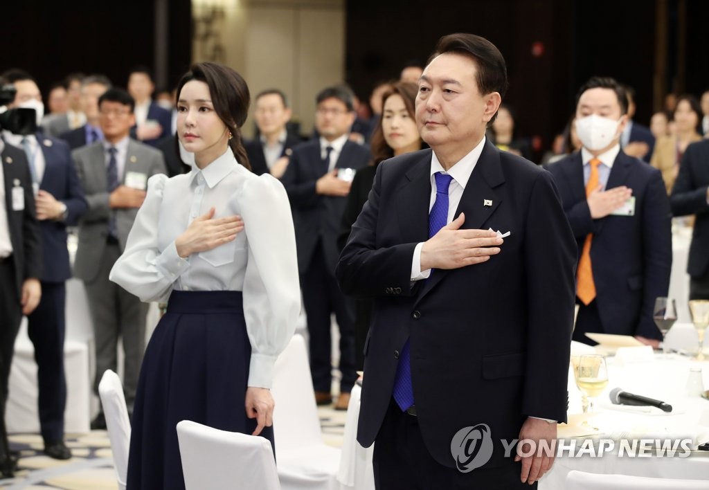 El presidente, Yoon Suk Yeol, y la primera dama, Kim Keon Hee, hacen un saludo a la bandera surcoreana, el 14 de enero de 2023 (hora local), en una reunión con residentes surcoreanos en los EAU, en un hotel, en Abu Dabi.