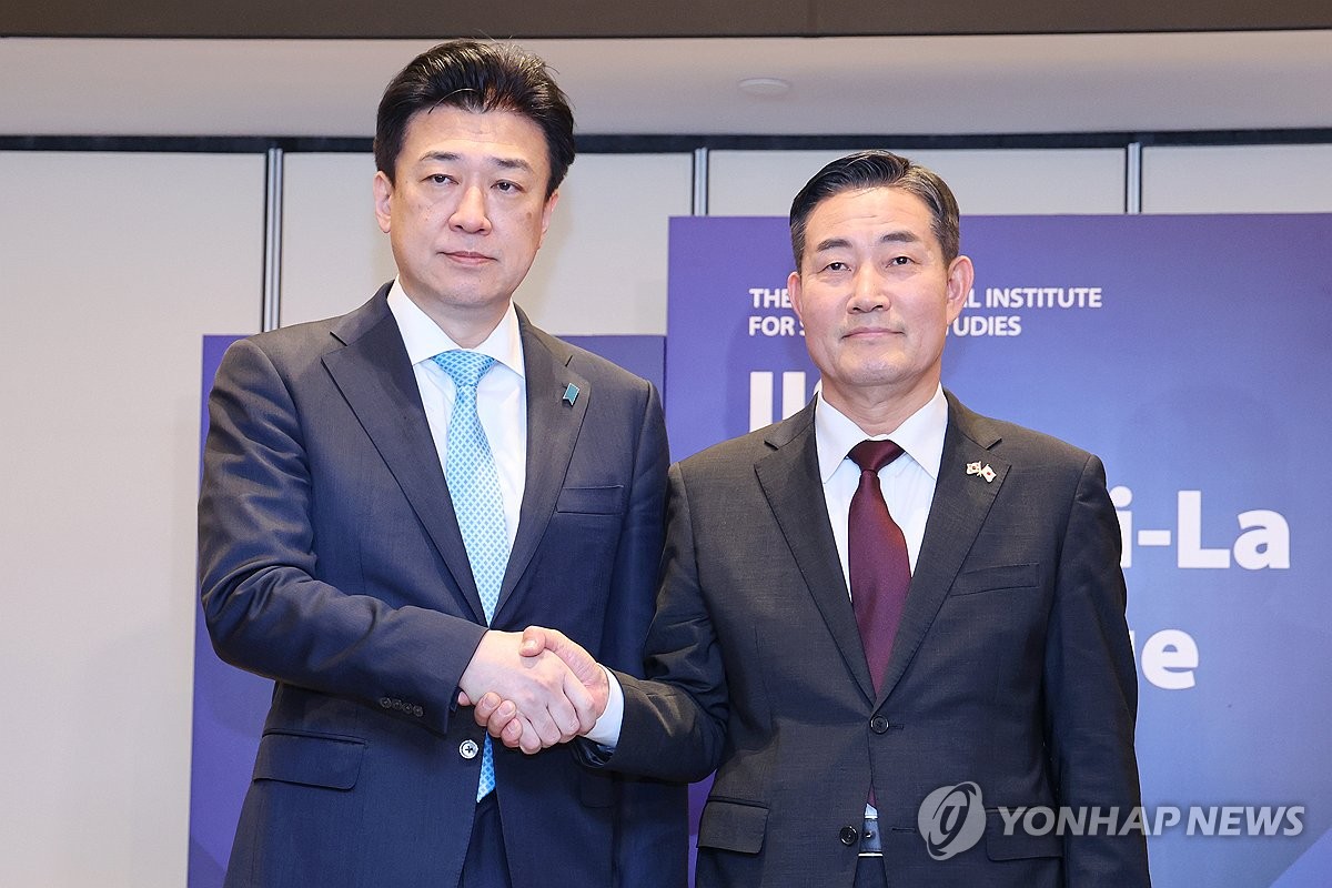 South Korean Defense Minister Shin Won-sik (R) and his Japanese counterpart, Minoru Kihara, shake hands during their meeting held on the sidelines of the Shangri-La Dialogue in Singapore on June 1, 2024. (Yonhap)