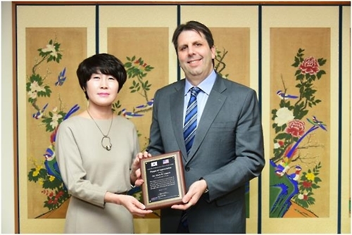 U.S. Ambassador to Korea Mark Lippert (R) poses with ASOK Chair Kim Hyun-sook, holding an appreciation plaque awarded by the association, during an event in Seoul on Jan. 12, 2017. (photo courtesy of ASOK)