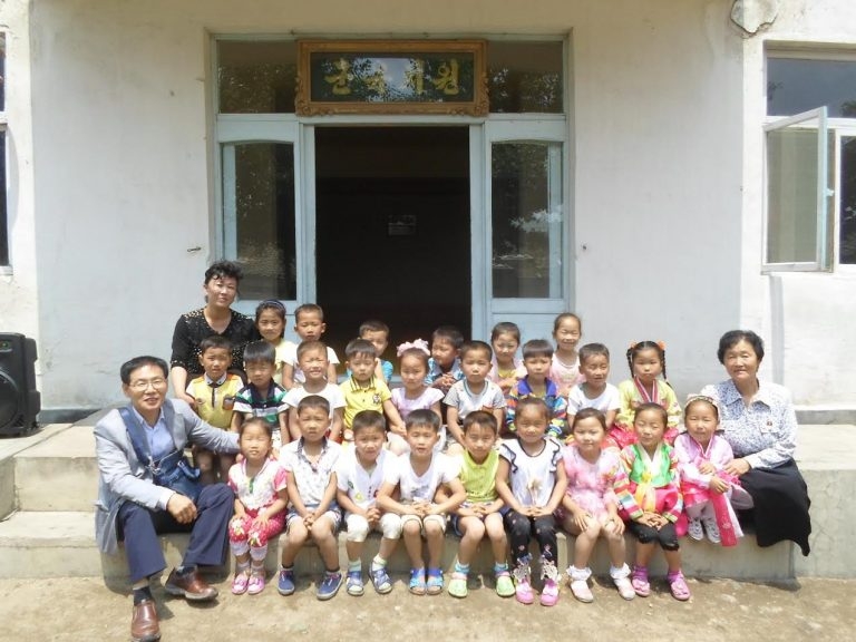 This undated photo, taken from the website of the London-based Love North Korean Children on June 13, 2017, shows the charity group's leader George Rhee (far L, front) posing for a photo with children during a monitoring visit to the North. (Yonhap)