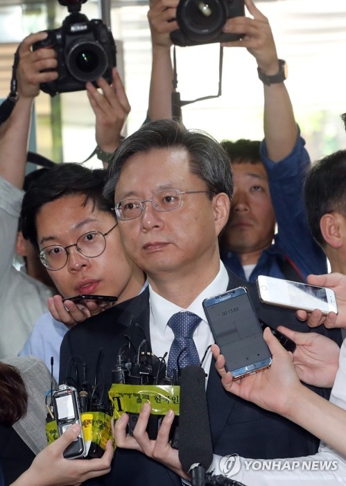 Woo Byung-woo, the former presidential secretary for civil affairs, is surrounded by reporters as he enters a courthouse in Seoul on June 16, 2017. He was to stand his first trial over his involvement in an influence-peddling scandal that led to the removal of former President Park Geun-hye. (Yonhap)