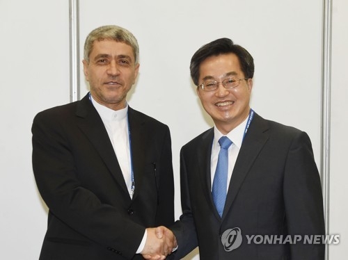 South Korea's Finance Minister Kim Dong-yeon shakes hands with his Iranian counterpart Ali Tayebnia on the sidelines of the second annual meeting of the Asian Infrastructure Investment Bank that began in South Korea's southern resort city of Jeju on June 16, 2017, in this photo provided by Kim's ministry. (Yonhap)