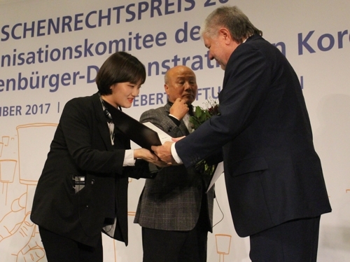 Jang Ae-jin (L), a survivor of the 2014 Sewol ferry sinking, receives the 2017 FES Human Rights Award from Kurt Beck, head of the German political foundation Friedrich-Ebert-Stiftung (FES), during a ceremony in Berlin on Dec. 5, 2017. Jang received the award on behalf of South Koreans who took part in candlelight rallies last year to call for then-President Park Geun-hye's resignation over an influence-peddling scandal. (Yonhap)
