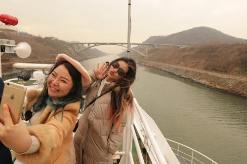 Tourists take pictures on board a cruise ship plying the Ara Waterway. (Yonhap) 