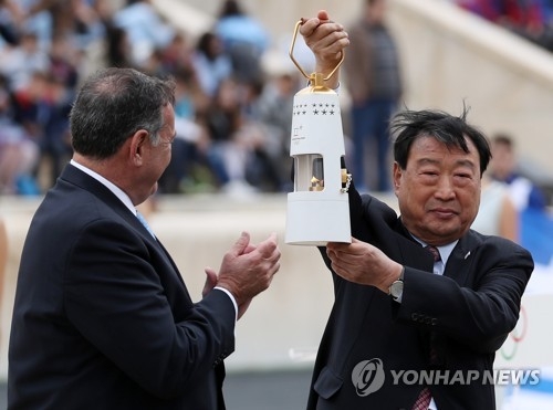 In this file photo taken Oct. 31, 2017, Lee Hee-beom (R), head of the 2018 PyeongChang Winter Olympics organizing committee, holds up a lamp containing the Olympic flame during a ceremony at the Panathenaic Stadium in Athens. (Yonhap)