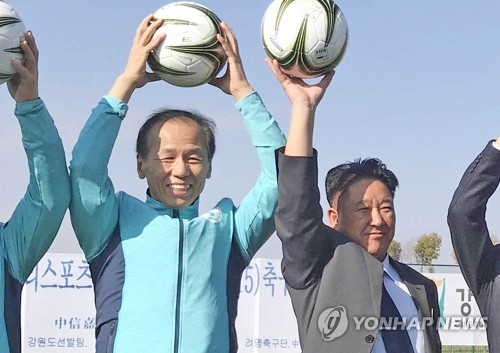 This photo provided by Gangwon Province shows Gangwon Governor Choi Moon-soon (L) posing for a photo with Mun Ung, the chairman of North Korea's April 25 Athletic Committee, at the Ari Sports Cup youth football tournament in Kunming, China, on Dec. 19, 2017. (Yonhap)