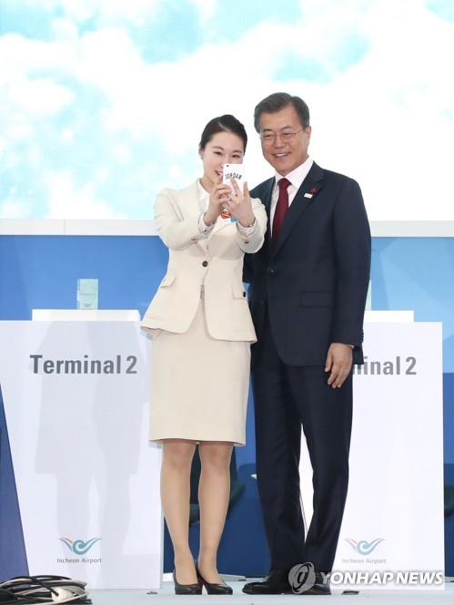 President Moon Jae-in (R) poses for a selfie with an airport worker at a ceremony marking the construction of a second passenger terminal at Incheon International Airport on Jan. 12, 2018. (Yonhap)