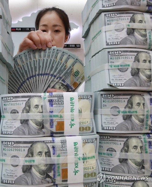 This file photo shows an employee of KEB Hana Bank in Seoul checking U.S. dollars. (Yonhap)