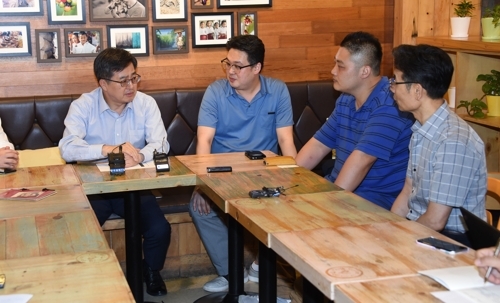Finance Minister Kim Dong-yeon (L) talks with a group of small shop owners in a Seoul restaurant, on Aug. 1, 2018. (Yonhap)