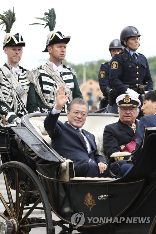 South Korean President Moon Jae-in (L) waves while riding through Stockholm streets in a carriage seated together with King Carl XVI Gustaf for a welcoming ceremony at the Royal Palace on June 14, 2019. (Yonhap)