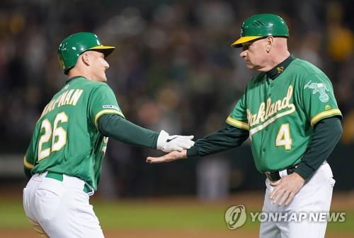In this Getty Images file photo from May 10, 2019, Matt Williams (R), third base coach of the Oakland Athletics, congratulates Matt Chapman after Chapman's walk-off solo home run against the Cleveland Indians in the bottom of the 12th inning of a Major League Baseball regular season game at Oakland Coliseum in Oakland, California. (Yonhap)