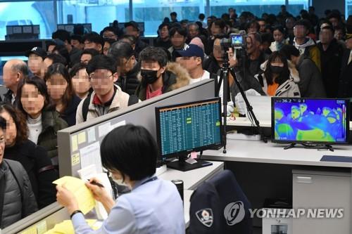 This undated file photo shows international passengers undergoing a body temperature scan at an international airport in South Korea. (Yonhap)