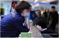 A South Korean quarantine official (L) checks the temperature of a person who just arrived at Incheon International Airport, west of Seoul, on Jan. 23, 2020. The National Quarantine Station is operating health checkpoints at all major airports to screen people for fever and other symptoms of the Wuhan coronavirus. (Yonhap)