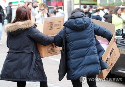 This file photo shows foreign travelers holding boxes of facial masks in Seoul. (Yonhap)