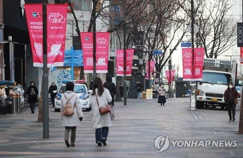 A few people walk on a street in Myeongdong in downtown Seoul on Feb. 8, 2020. The normally busy tourist district was nearly empty amid growing fears of the new coronavirus. (Yonhap)