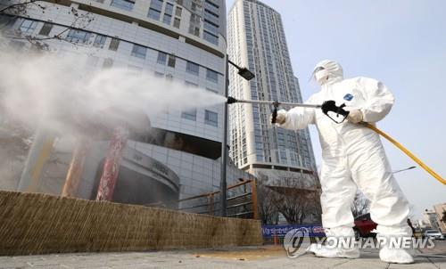 A Seongdong Ward quarantine worker disinfects the street outside a community health service center that was used by a person who tested positive for the coronavirus on Feb. 19, 2020. (Yonhap)