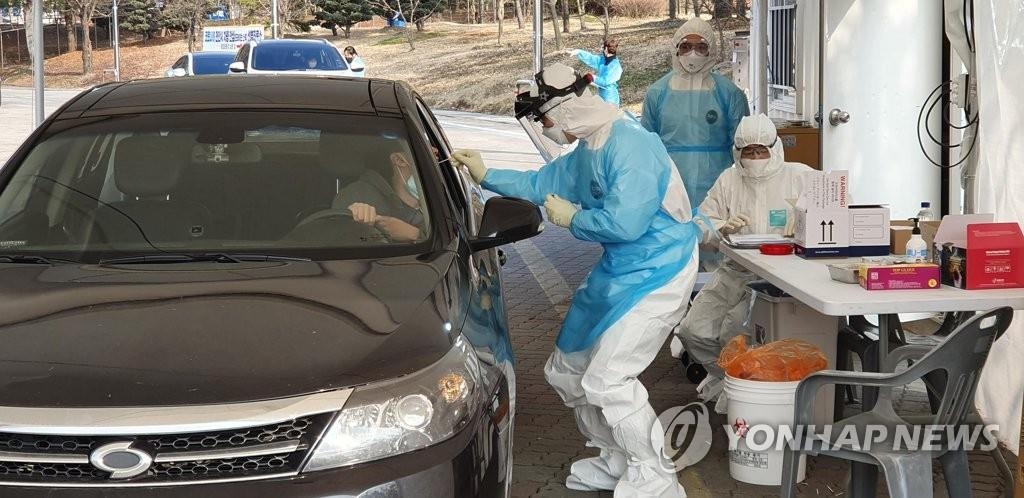 A medical worker collects a sample from a citizen in an automobile at a drive-through clinic in Cheonan, 90 kilometers south of Seoul, on Feb. 29, 2020, to test for the new coronavirus. (Yonhap)