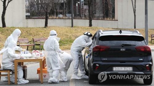 Quarantine officials carry out medical check-ups at a drive-thru examination center set up near the main government complex in Sejong, 130 kilometers south of Seoul, on March 13, 2020. (Yonhap)