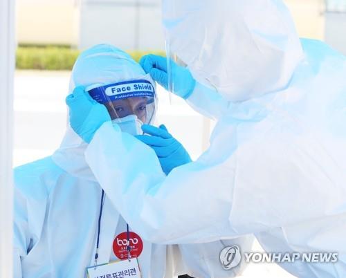 Election officials check their protective suits at a polling station in Yongin, south of Seoul, on April 11, 2020. (Yonhap)