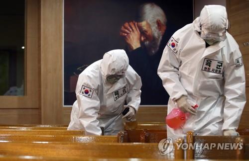 Military medical officials clad in protective suits disinfect chairs at a church in Daegu on April 16, 2020. (Yonhap)