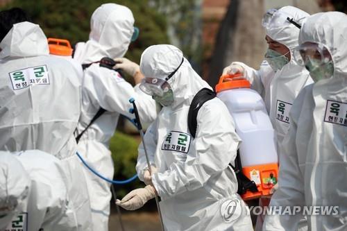 This photo taken on April 16, 2020, shows military medical officials clad in protective suits preparing to work at a middle school in Daegu. (Yonhap)