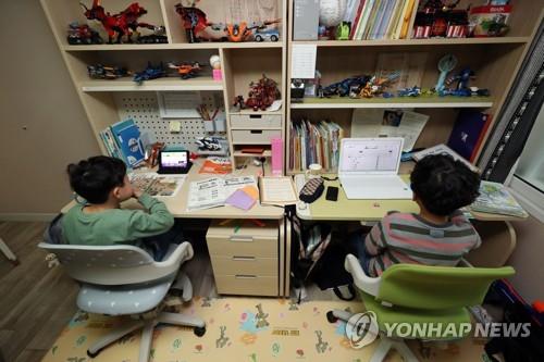 Two children, first and third graders, attend online classes via a tablet and notebook PC at their home in Gwangju, southwestern South Korea, on April 20, 2020. (Yonhap)