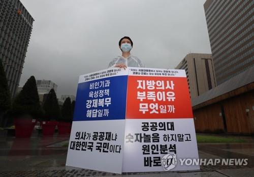 A doctor from Seoul National University Hospital holds a sign in protest of the government's medical reform plan on Aug. 29, 2020, despite doctors ending their three-day walkout a day earlier. (Yonhap)