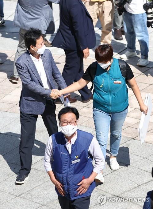 Kwon Jeong-oh (L), head of the Korean Teachers and Education Workers Union (KTU) shakes hands with a union member outside the Supreme Court on Sept. 3, 2020. (Yonhap)