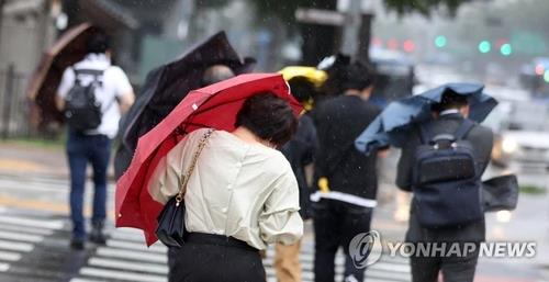 This undated file photo shows citizens crossing a street amid rain and strong wind. (Yonhap)