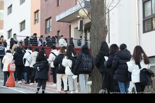 Exam takers wait in line to receive body temperature checks before entering a building at Soongsil University in Seoul on Dec. 4, 2020, to take the school's essay test as part of a procedure to gain admission to the university. The essay test came one day after they sat for the state-administrated scholastic aptitude test. (Yonhap)