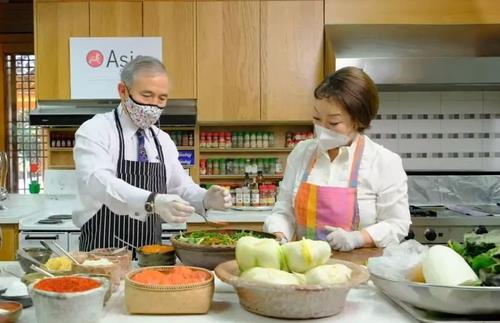 U.S. Ambassador to South Korea Harry Harris (L) learns how to make kimchi with Chef Lee Hye-jung at the Habib House, his official residence in Seoul, on Dec. 15, 2020, in this photo captured from the Facebook account of the Asia Korea Society Center. (PHOTO NOT FOR SALE) (Yonhap)