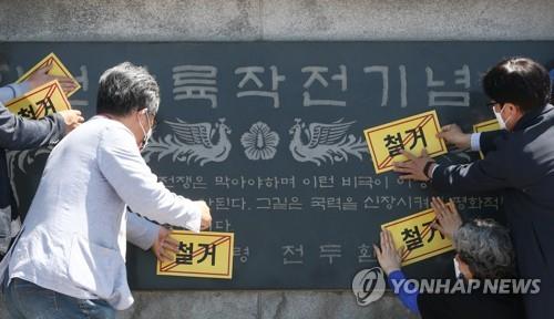 Civic activists attach demolition stickers to a stone monument related to former President Chun Doo-hwan during a rally in Incheon, west of Seoul, on May 18, 2021. (Yonhap)