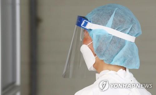 A health worker at a COVID-19 testing center has a flushed face from the sweltering heat on July 21, 2021. (Yonhap)