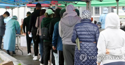 This undated file photo shows foreign workers in line to get tested for COVID-19 in Seoul. (Yonhap)