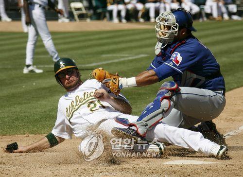 In this EPA file photo from Sept. 6, 2006, Gerald Laird of the Texas Rangers (R) puts a tag on Mark Kotsay of the Oakland Athletics during the bottom of the sixth inning of a Major League Baseball regular season game at McAfee Coliseum in Oakland. (Yonhap)