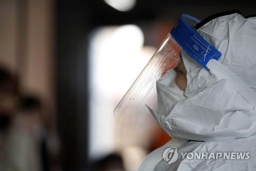 A health worker closes their eyes while working at a makeshift COVID-19 testing station in the southwestern city of Gwangju on Jan. 21, 2022, in this photo provided by a local government. (PHOTO NOT FOR SALE) (Yonhap) 