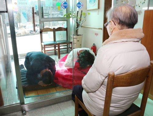 This photo taken on Jan. 31, 2022, and provided by Chilgok County shows people performing a formal Korean bow, called "sebae," to their mother at a nursing home in Chilgok, North Gyeongsang Province, with the glass door closed due to the spreading omicron variant. (PHOTO NOT FOR SALE) (Yonhap)
