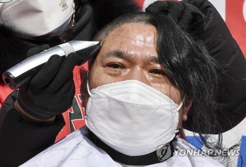 A small merchant has his hair shaven in a protest rally against state anti-virus measures near Gwanghwamun Square on Feb. 15, 2022. (Yonhap)