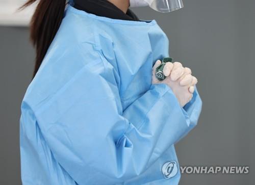 A medical worker warms her hands with an instant hot pack at a makeshift COVID-19 testing station in Seoul on Feb. 17, 2022, amid a cold wave throughout the country. (Yonhap)