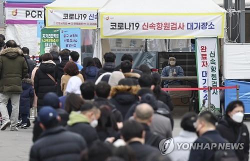 People stand in line to take coronavirus tests at a screening clinic in Seoul's Songpa Ward on March 8, 2022. 