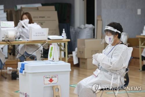 Election officials clad in protective gear await COVID-19 patients and those in quarantine at a polling station in Seoul on May 28, 2022, the final day of two-day early voting for the June 1 local elections. (Yonhap)