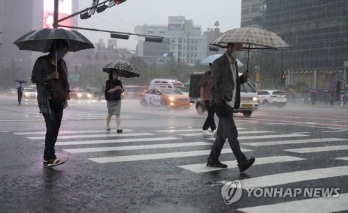 Citizens go to work in Seoul's Gwanghwamun area amid heavy downpours on June 30, 2022. (Yonhap)