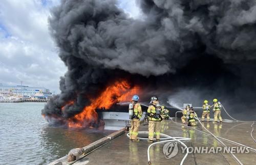 This photo provided by a fire station shows firefighters working to put out a fire on fishing boats at Jeju Island's Hallim Port on July 7, 2022. (PHOTO NOT FOR SALE) (Yonhap)