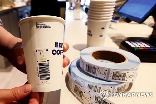 This file photo shows a barcode sticker pasted on a disposable cup during an environment ministry-hosted demonstration of a deposit-return scheme at a cafe in central Seoul in May. (Yonhap)