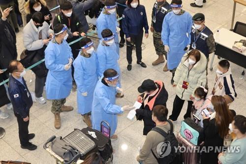 Quarantine officials in blue gowns guide travelers arriving from China to undergo a PCR test at Incheon International Airport, west of Seoul, on Jan. 2, 2023. (Yonhap)