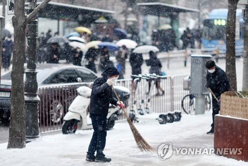 People remove snow from a street in Seoul on Jan. 26, 2023. (Yonhap)