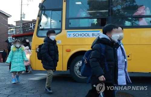 Students wearing face masks get off a school bus in Seoul on Jan. 30, 2023. (Yonhap) 
