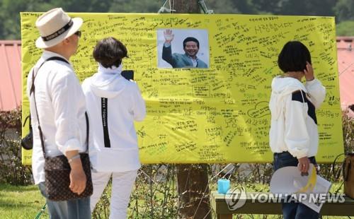A board carrying a photo of late former President Roh Moo-hyun and people's condolence messages for him stands near the tomb of Roh at Bongha Village in the southeastern city of Gimhae on May 23, 2023, to mark the 14th anniversary of Roh's death the same day. (Yonhap)